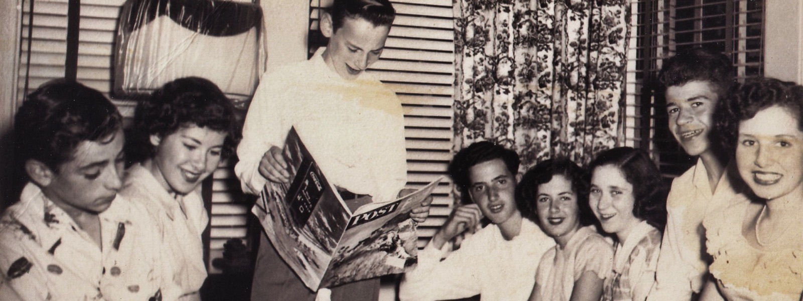 A group of teenagers gathered around a copy of the Saturday Evening Post, about 1949